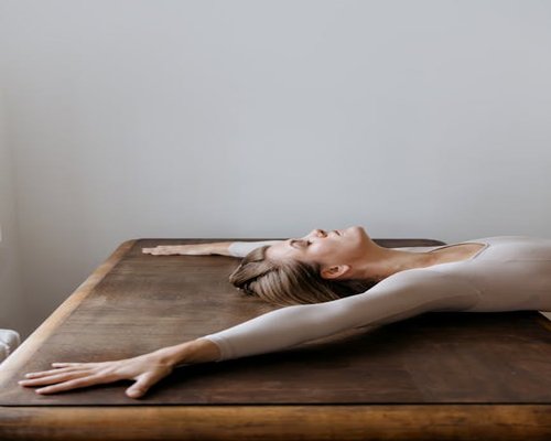 Person stretching arms upwards next to a desk to relieve tension